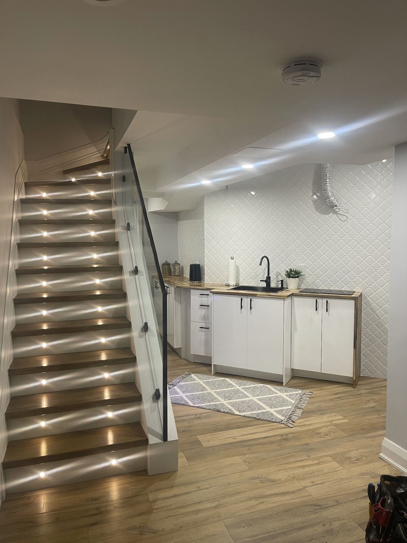 Stair tread lights glowing on a staircase down to a basement suite