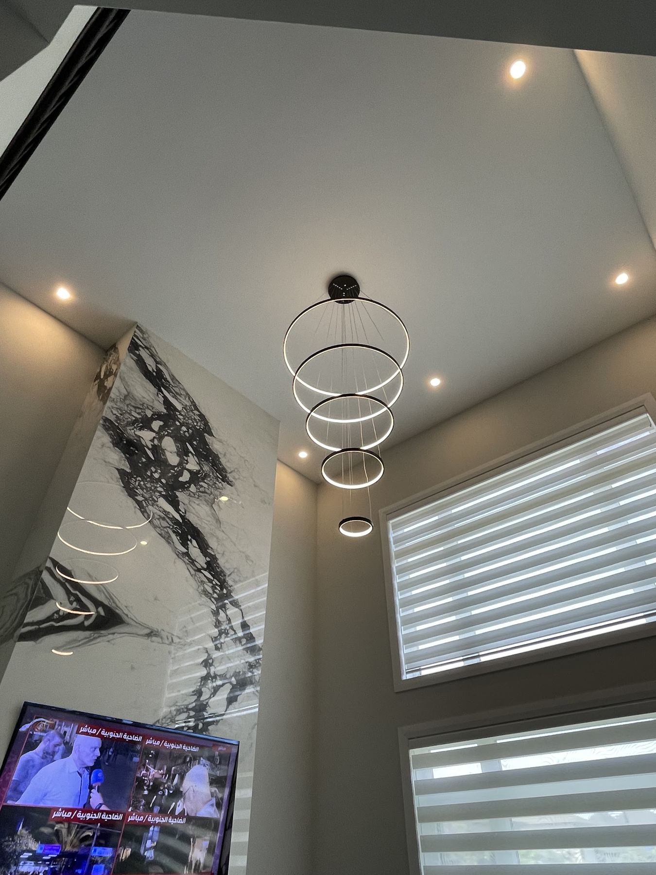 A multi-ring LED chandelier hanging in a two-storey foyer