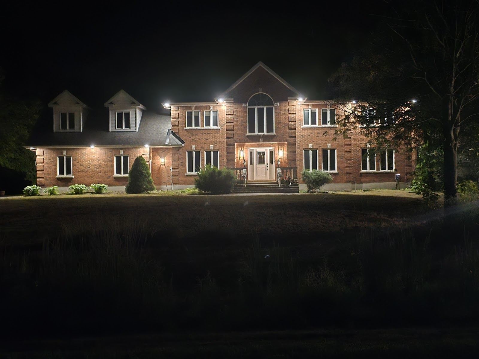 A brick house at night lit by soffit pot lights